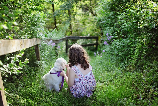 Kleines Mädchen mit kleinem Hund im grünen Garten